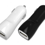 Juodas įkroviklis automobilinis Tellos su USB jungtimi šalia balto įkroviklio