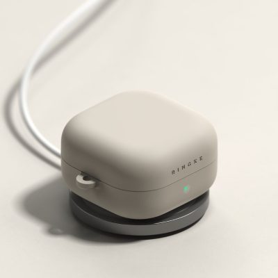 Akmens spalvos Ringke Silicone dėklas Samsung Galaxy Buds 4/4 Pro su LED indikatoriumi, matomas ant įkrovimo stovo