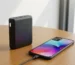Power bank prijungtas prie telefono ant medinio stalo